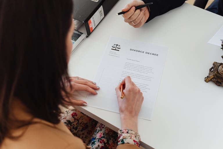 A person signing a divorce decree document with focus on hands and paper.